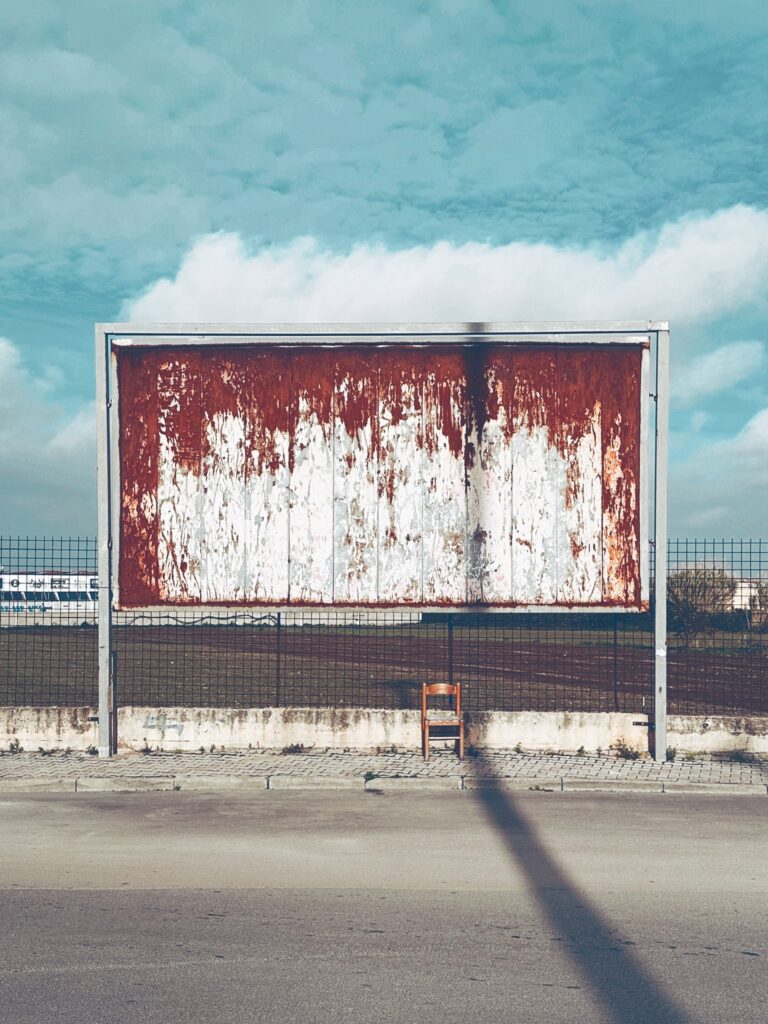 Persiinloro series by Sofia Dell'Aversano Orabona: a rusty empty billboard by the road under a blue sky