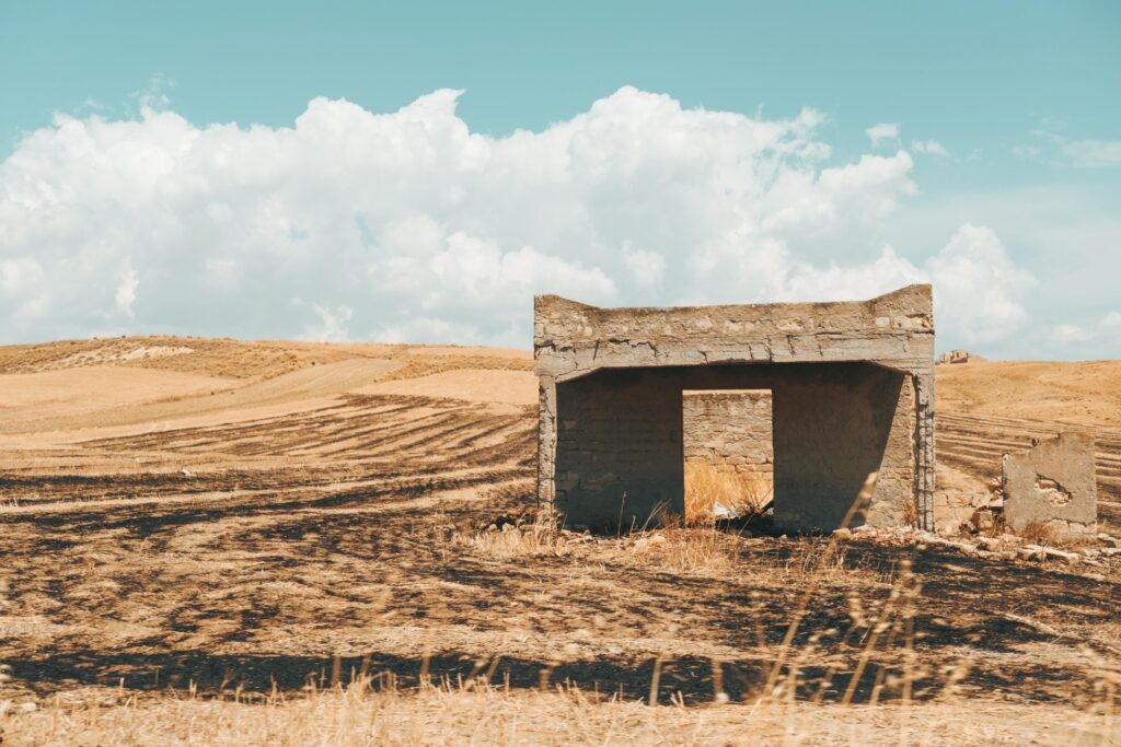 Persiinloro series by Sofia Dell'Aversano Orabona: a ruined stone hut in a golden field under clouds
